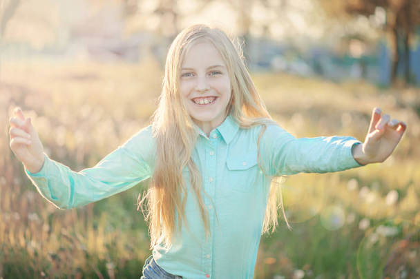 Beautiful smiling teenage girl in blouse, against green of summe - Photo, image