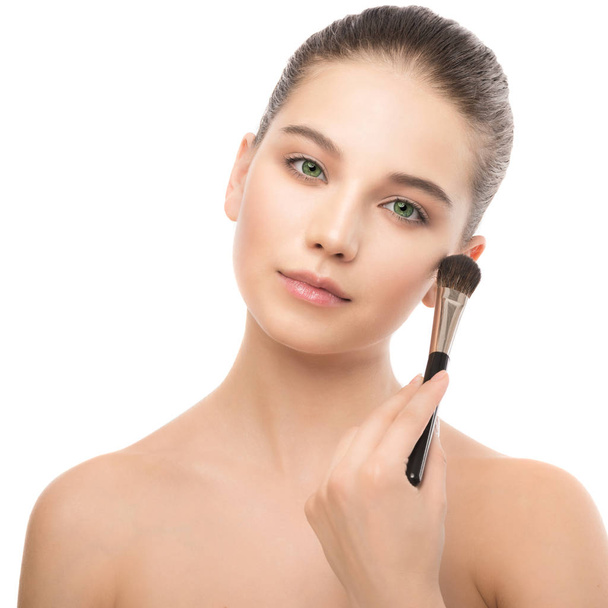 Young brunette woman with clean face. Girl perfect skin applying cosmetic brush. Isolated on a white. - Foto, immagini