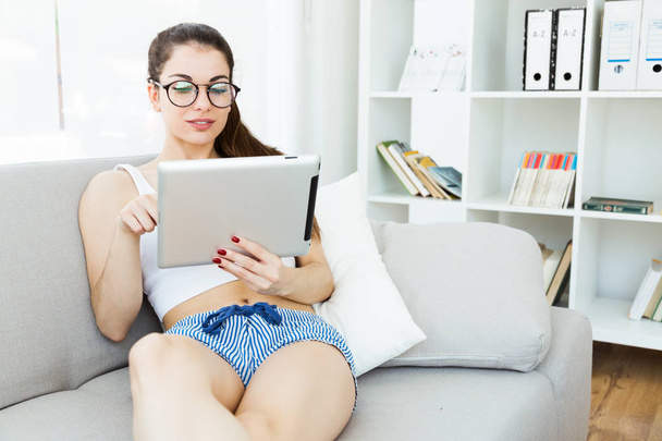 Beautiful young woman using her digital tablet at home. - Fotó, kép