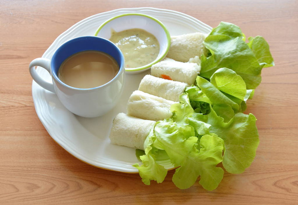 булочка с фаршированной колбасой и зеленый дуб с чашкой кофе на блюде
 - Фото, изображение