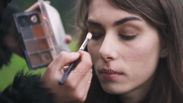 Make up artist's applying eyeshadow  with a brush on woman's eye - Кадры, видео