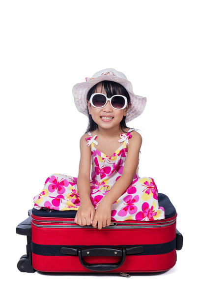 Happy Asian Little Chinese girl sitting on a suitcase - Φωτογραφία, εικόνα