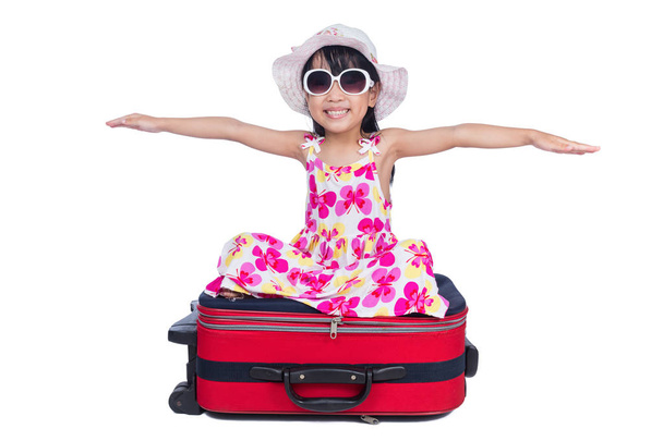 Happy Asian Little Chinese girl sitting on a suitcase - Foto, afbeelding