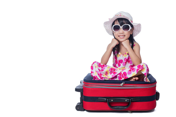 Happy Asian Little Chinese girl sitting on a suitcase - Foto, afbeelding