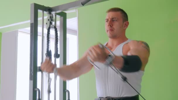 Athletic young man working out on fitness exercise equipment at gym - Footage, Video