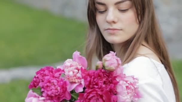 Woman makes peonies bouquet sitting in park - Filmati, video