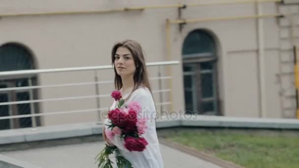 Woman walking in city with bouquet of flowers - Filmati, video