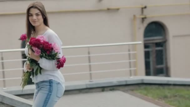 Woman walking in city with bouquet peonies flowers - Video
