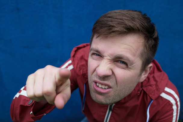 θυμωμένος άνθρωπος σε κόκκινο παλτό κοιτώντας ψηλά - Φωτογραφία, εικόνα