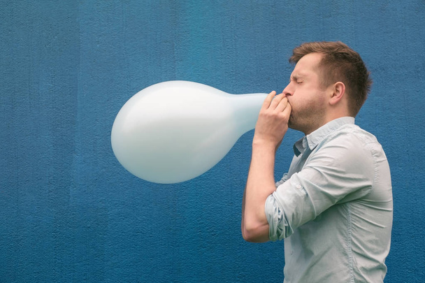 Man blowing up a balloon - 写真・画像