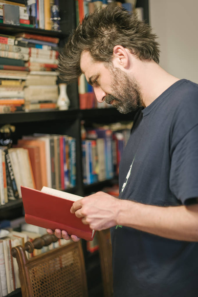 Homme curieux de choisir le livre dans sa bibliothèque à la maison
 - Photo, image