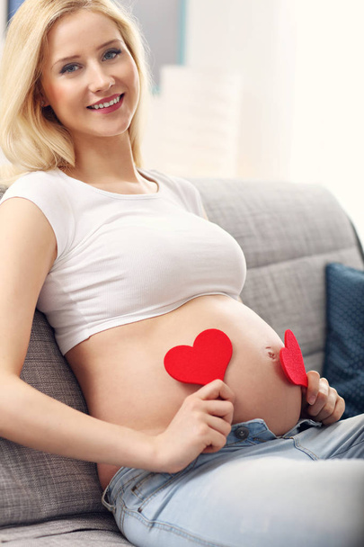 Ευτυχισμένος εγκύου γυναίκας που αναπαύεται στον καναπέ - Φωτογραφία, εικόνα
