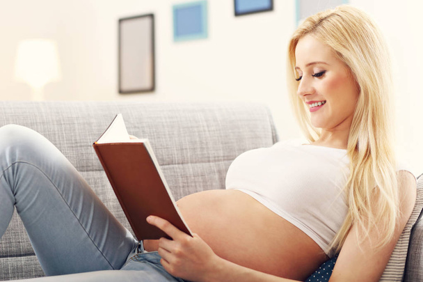 Щаслива вагітна жінка відпочиває на дивані
 - Фото, зображення