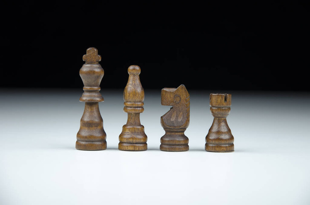 Conjunto de figuras de xadrez de madeira preta em um fundo preto e branco borrado com reflexão
 - Foto, Imagem
