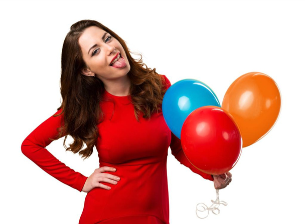 Beautiful young girl holding balloons and taking out her tongue - Фото, изображение
