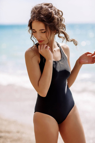 High fashion look.glamor beautiful sexy stylish brunette young female model with bright make-up, with perfect sunbathing clean skin in a black swimsuit on the beach in fashion style - Фото, изображение
