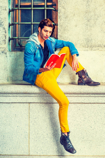 Jeune homme lisant un livre rouge, assis dans la rue
 - Photo, image