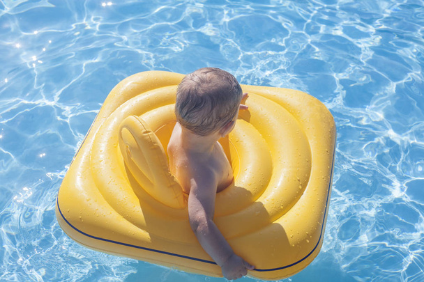 Baby boy with yellow rubber ring on swimming pool - Foto, immagini