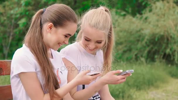 Happy girlfriends with smartphone in the park - Footage, Video