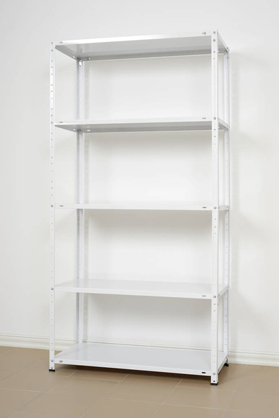 white metal rack near the wall, empty shelves - Photo, Image
