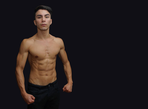 Fiatal latino férfi fekete nadrág, félmeztelen, jelent a testépítő-fekete háttér - Fotó, kép