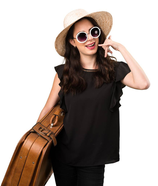 Beautiful young girl with  a suitcase making phone gesture - Foto, Imagem