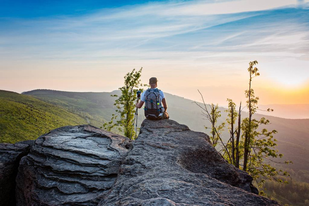 Τουριστική άνθρωπος που κάθεται στην κορυφή του λόφου στο sunrise - Φωτογραφία, εικόνα