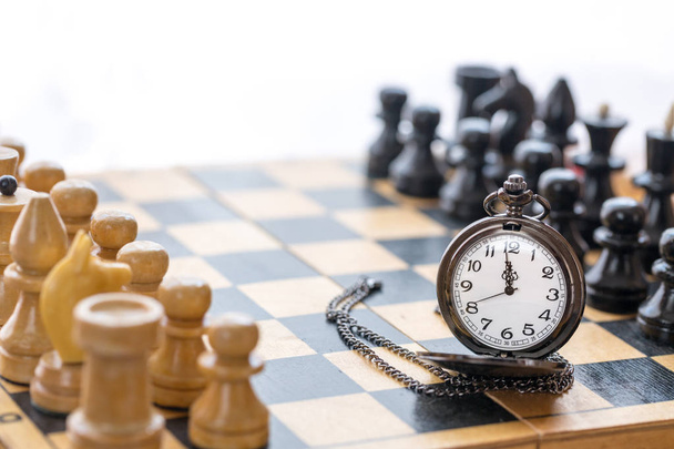 Reloj de bolsillo vintage y piezas de ajedrez en tablero de ajedrez
 - Foto, Imagen