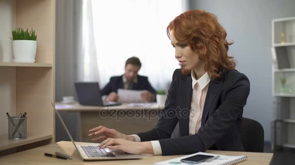 Woman typing on laptop, taking cellphone to check information, company employee - Metraje, vídeo