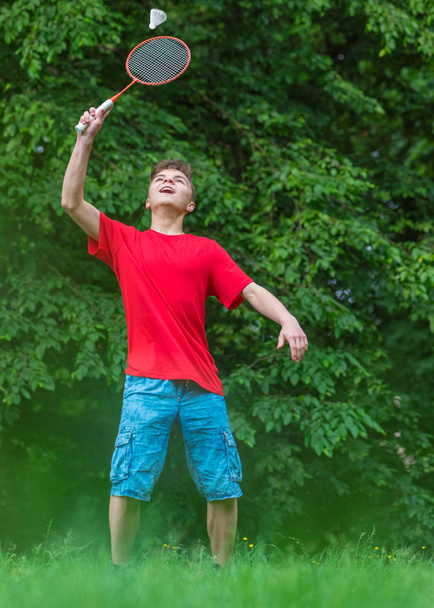 Teen boy playing badminton in park - 写真・画像