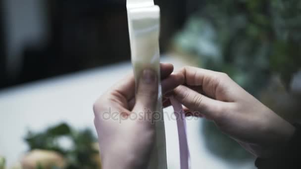 Κοντινό πλάνο λουλούδι κατάστημα Βοηθός κάνοντας μια διακόσμηση κορδέλα - Πλάνα, βίντεο