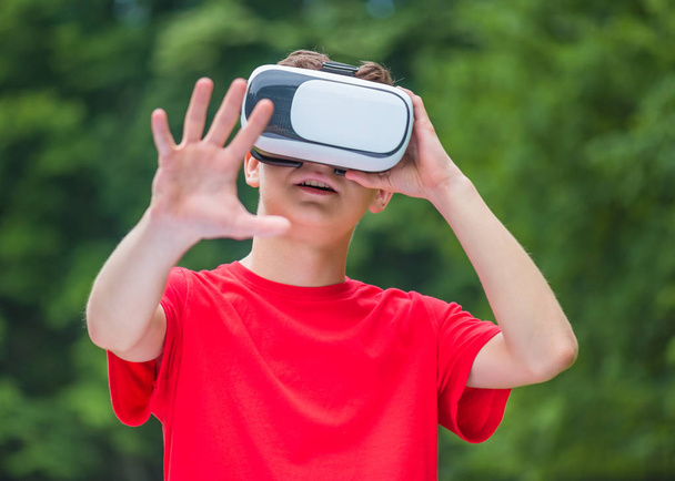 Teen boy with VR glasses in park - Foto, immagini