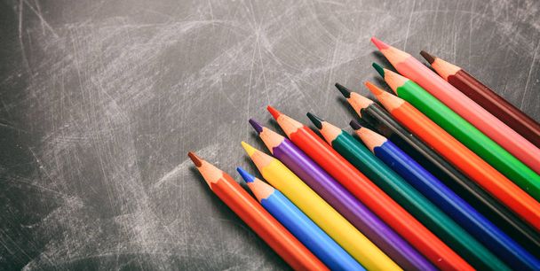 Colored pencils on a black board - Фото, изображение