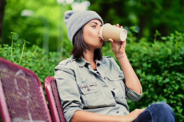 Mujer bebe café en un parque de verano
 - Foto, Imagen