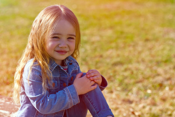 Jeans yeşil bir arka plan üzerinde dağınık saçlı güzel sevimli küçük kız - Fotoğraf, Görsel