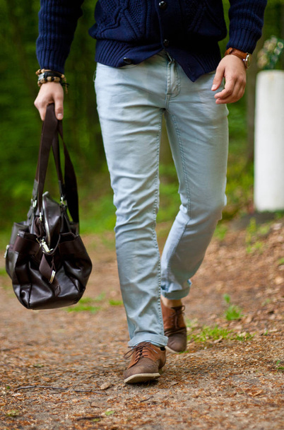 фотография молодого модного человека, прогуливающегося на улице с сумкой в руке
 - Фото, изображение