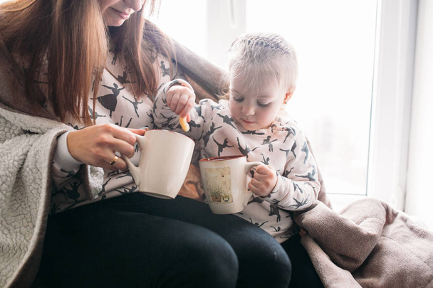 Mamma e figlia bere qualcosa con tazza
 - Foto, immagini