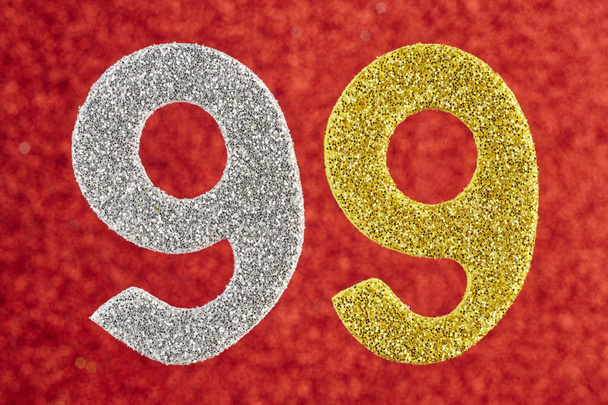 Číslo devadesát devět stříbrných žluté barvy na červené pozadí. O - Fotografie, Obrázek