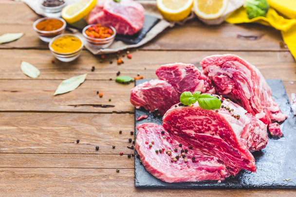 Top view raw pork steak and garlic, pepper on wooden background. Fresh meat - Foto, afbeelding