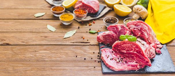 Raw juicy meat steak on dark wooden background - Foto, afbeelding