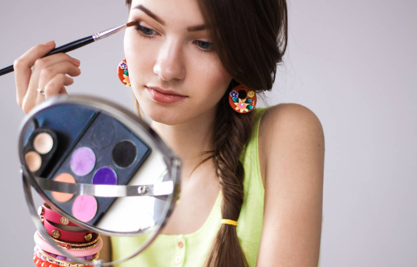 Young beautiful woman making make-up near mirror,sitting at the desk - Fotografie, Obrázek