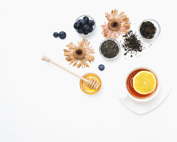 Gyógynövény tea mézzel, vad bogyó és virágok fehér háttér. Lapos feküdt, másol hely  - Fotó, kép