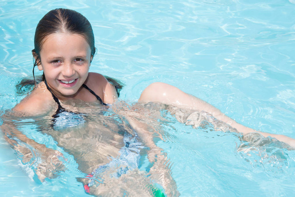 mooi meisje kind baadt in het zwembad van het hotel - Foto, afbeelding