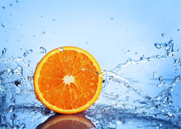 Mehukas puoli appelsiinia sinisessä vedessä
 - Valokuva, kuva