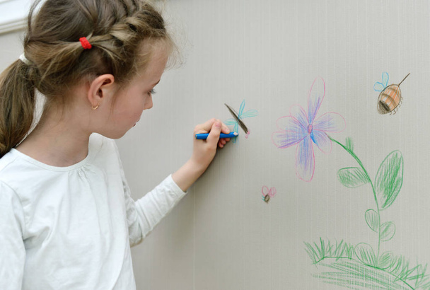 Little girl drawing on the wallpaper with pencil. - Foto, imagen