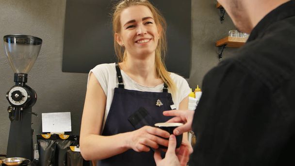 Waitress serving customer over the counter at a coffee shop - Fotoğraf, Görsel