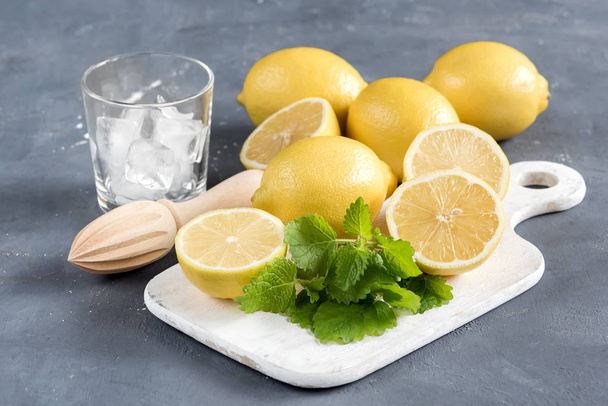 Ingredients for refreshment summer drink. Traditional ingredients for lemonade with lemon mint and ice Wooden squeezer Mint leaf - Photo, Image