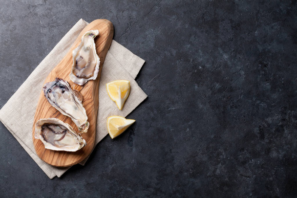 Opened oysters and lemon - Фото, изображение