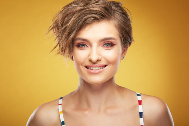 Closeup portrait of sexy happy young pretty female model with short disheveled brown hair, and sincere smiling face, posing in studio on yellow background - Photo, Image