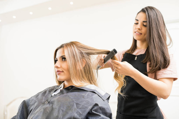 hairstylist using hair straightener - Foto, Imagem